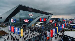 Vista aérea do Salão de Pequim 2026 mostrando centro de convenções lotado com bandeiras de marcas automotivas chinesas e multidão de visitantes