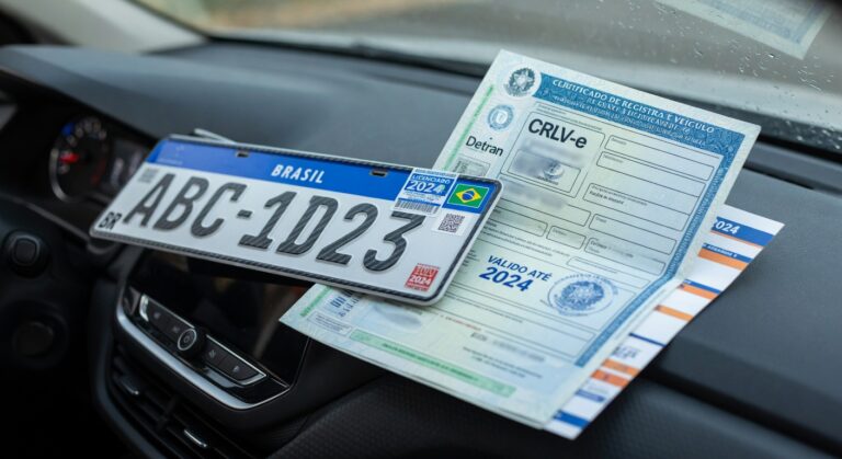 Brazilian vehicle registration documents and license plate on car dashboard representing Detran-RJ licensing deadline extension
