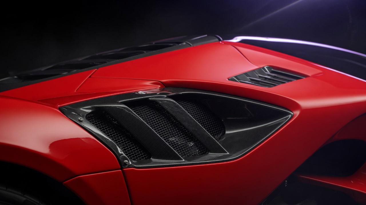 Close-up detail of a red Ferrari supercar showcasing its aerodynamic design elements and sculpted body lines