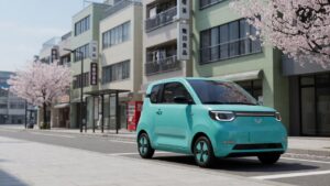 Carro elétrico compacto chinês estacionado em rua urbana de Tóquio com arquitetura japonesa ao fundo