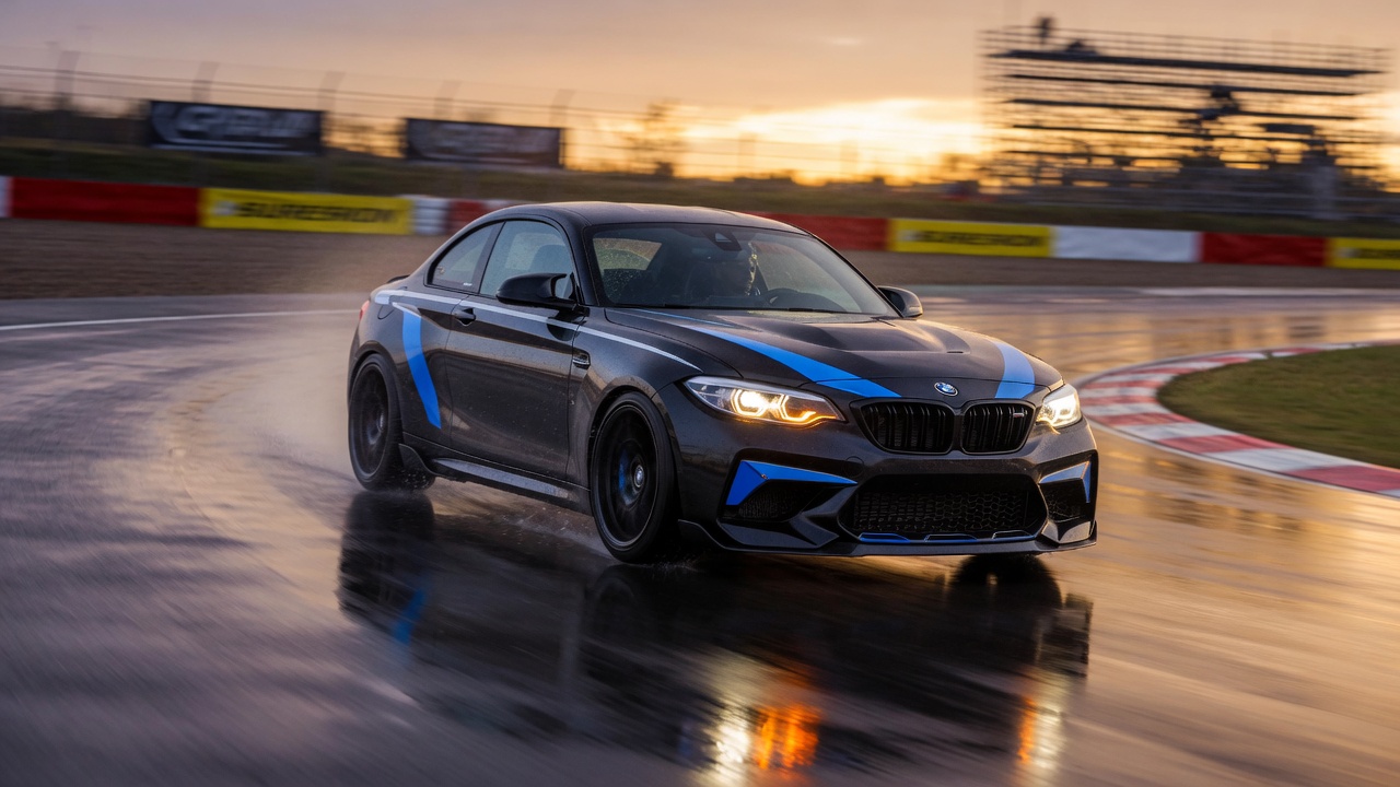 BMW M2 esportivo em movimento em pista de corrida, destacando seu sistema de tração integral e design agressivo