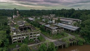 Vista aérea de complexo industrial abandonado da Ford na Amazônia com estruturas cobertas pela vegetação tropical