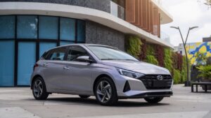 Novo Hyundai i20 2027 em prata metálico fotografado em ambiente urbano moderno, vista frontal três quartos