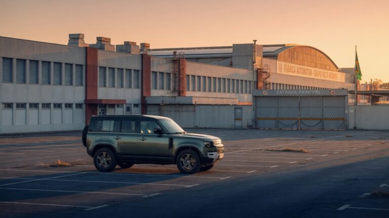 Land Rover SUV estacionado em frente a fábrica automotiva brasileira com portões fechados, simbolizando o encerramento da produção da marca no Brasil