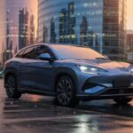 BYD Sealion 7 SUV elétrico azul metálico em ângulo frontal três quartos, estacionado em ambiente urbano brasileiro com iluminação dourada