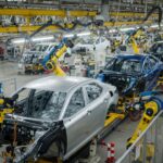 Linha de produção da Toyota em fábrica automotiva mostrando veículos em diferentes estágios de montagem