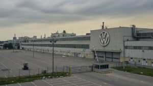 Fábrica da Volkswagen com portões fechados e estacionamento vazio, simbolizando possíveis cortes de empregos e fechamento de plantas industriais