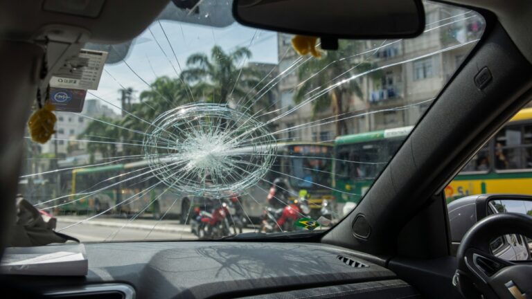 Para-brisa de carro com trinca visível em destaque, fotografia automotiva profissional mostrando dano que pode gerar multa