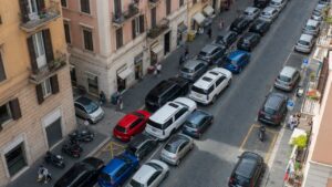 Grandes SUVs estacionados em rua estreita europeia demonstrando questões de espaço urbano e diferença de tamanho entre veículos