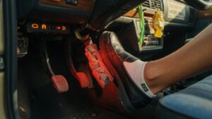 Close-up de pé de motorista pressionando pedal de freio borrachudo e macio no interior de um carro, evidenciando falha no sistema de freios