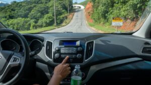Motorista ajustando controles do ar-condicionado no painel do carro enquanto dirige em uma ladeira íngreme