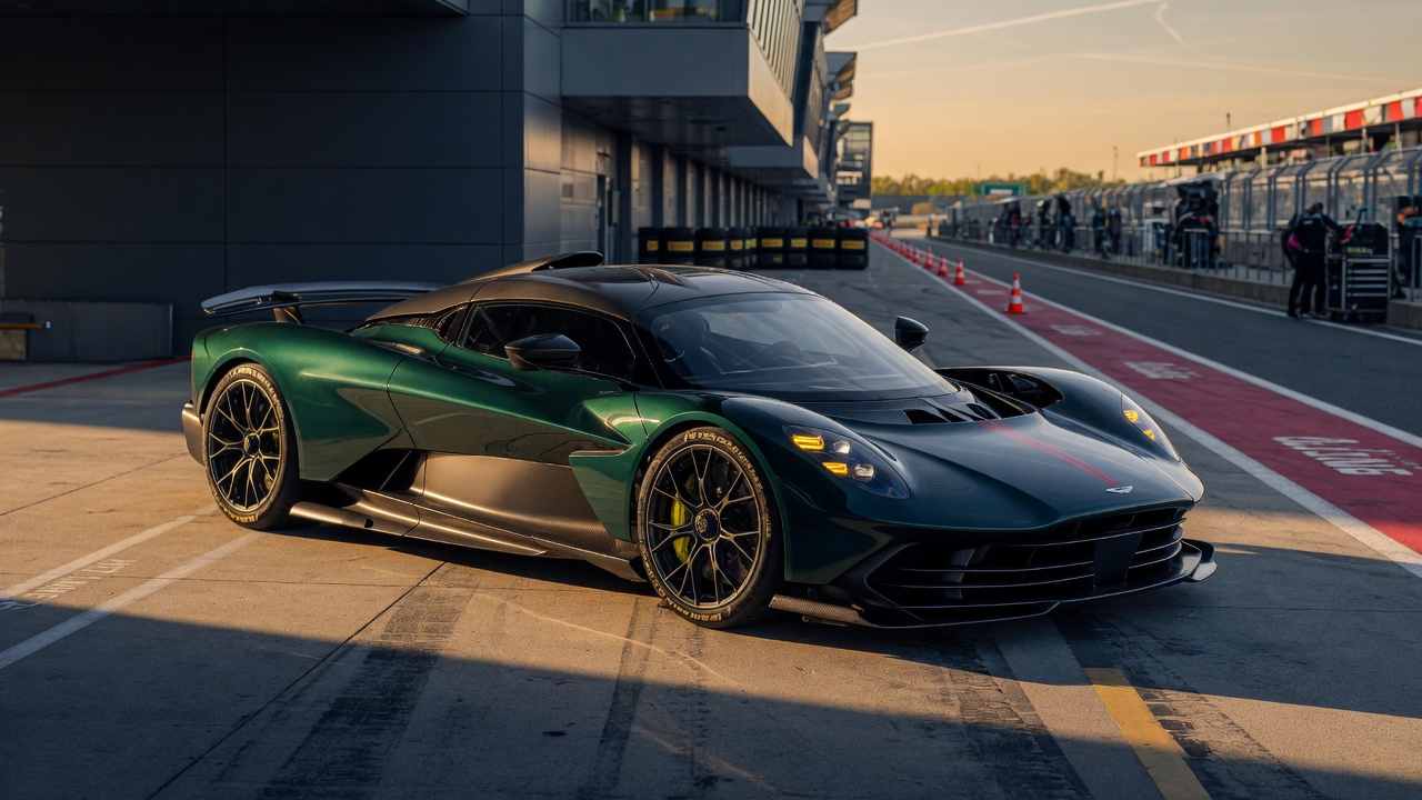 Aston Martin Valhalla em verde britânico estacionado em autódromo durante pôr do sol, destacando design aerodinâmico e elementos em fibra de carbono